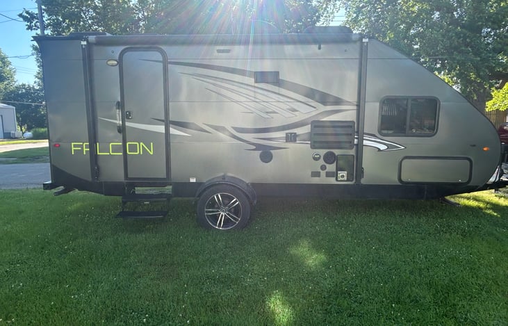 Camper exterior - entrance, awning, outside radio and front pass through storage.