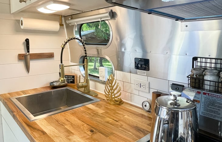 This gorgeous, custom DFW Airstream rental has upgraded walnut butcher block counter tops and a fully stocked modern farmhouse kitchen with a French press coffee maker, blender & convection microwave.