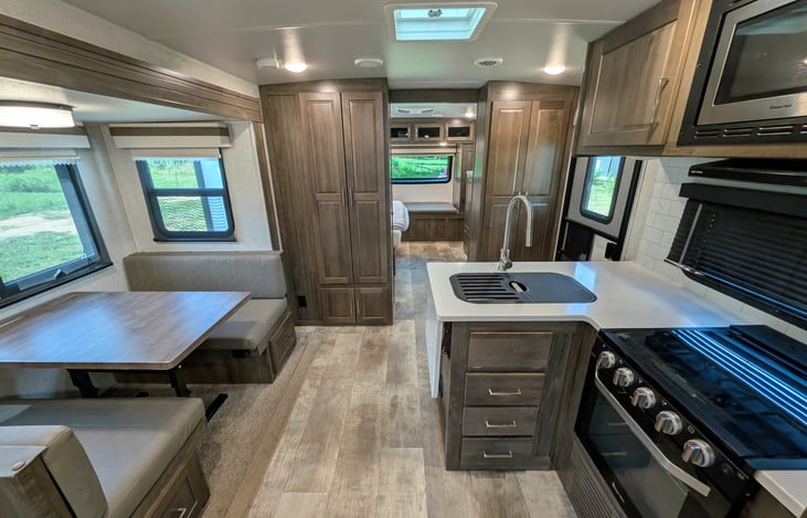 Spacious open-concept living area w/ dual recliners, TV & fireplace. Full kitchen features a residential fridge, 3-burner stove, oven, microwave, deep sink & booth dinette! Natural light throughout.