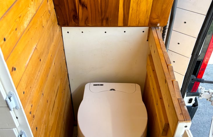 Towards the back of the van, there is a self contained toilet. Easy to sit in and tuck away. No it does not smell.