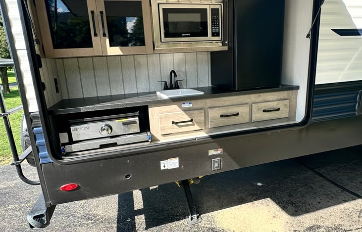 Outdoor kitchen with flat top griddle, microwave, sick and refrigerator