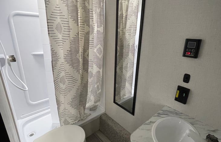 Bathroom with shower, toilet, sink and On-Demand hot water heater control.