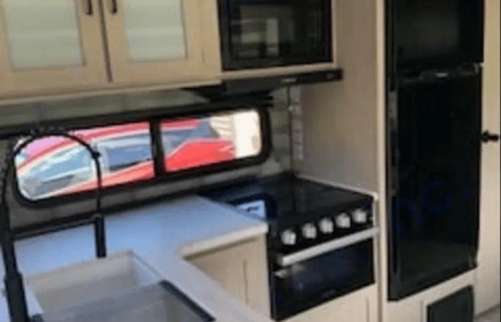 Spacious kitchen with double bowl sink, ample cupboard space, stove top with oven, built-in microwave, and refrigerator/freezer.