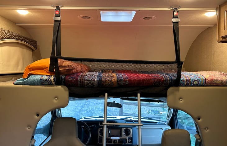 Bunk bed above cab is protected with netting and accessible by removable ladder. Privacy curtain, lighting and cup holders.