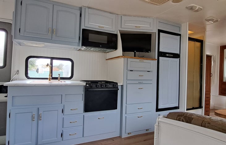 3-burner gas stove and oven, microwave, smart TV, sink with spray handle, plenty of storage and electric/propane fridge freezer.