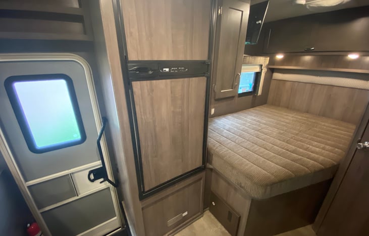 View of side door, fridge and back bed. RV comes with all linens and towels.