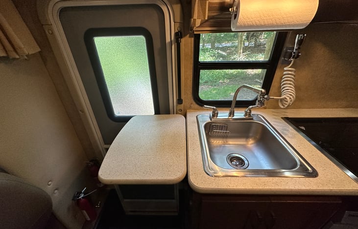 Kitchen sink with paper towel holder and extension spray faucet for easy cleaning. Additional prep table on the left
