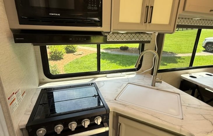 Full kitchen area with 3 Stove top burners, oven for making a quick pizza, sink, and microwave.