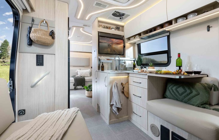 Kitchen with TV over sink, cabinets above and seating.