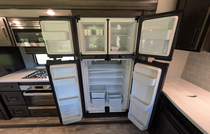 Gourmet galley & rear den retreat! Includes a 12 cu ft fridge, pantry, stove/oven, dual sofas, theater seats, 50" TV, electric fireplace, and 3 slides for spacious high-end living.
