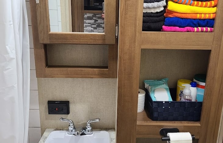 Bathroom stocked with towels, washcloths, hand towels and a few cleaning supplies.