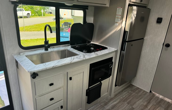 Fully equipped kitchen with large sink, propane cooktop, microwave and large refrigerator