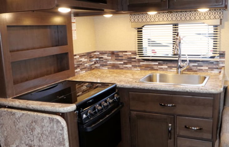 Full kitchen with sink, oven, stovetop, cabinets, counterspace, and extra fold-out counter