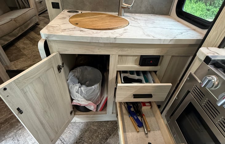 Base cabinet of the sink. We place a small trash can on the left. Some basic kitchen and silverware items in the drawers