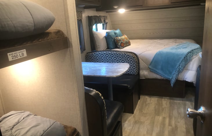 View from bathroom door.  Bunk bed (250 lb. capacity each) are to the left.  Dinette table to the left, kitchen to the right and Queen bed straight ahead.