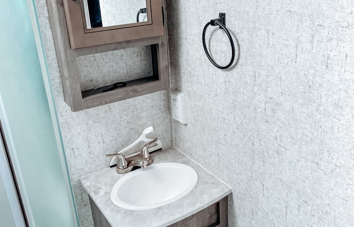 There is a sink and additional area to store any of your toiletries in the medicine cabinet above