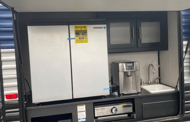 outdoor kitchen includes fridge/freezer, storage, sink, water/ice maker, pull out griddle