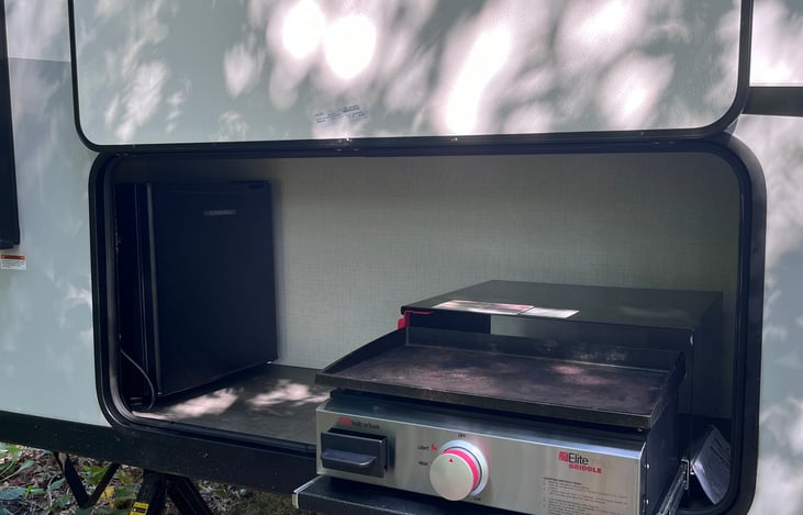 Outdoor kitchen with mini fridge and Lodge cast iron cooktop.