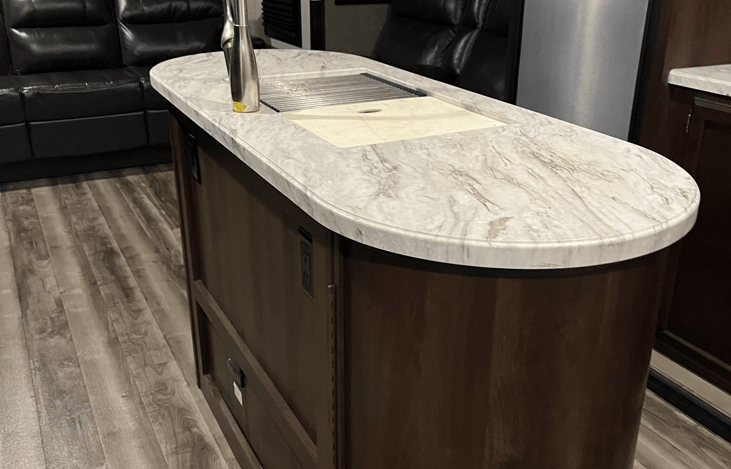 Kitchen has an island sink with food storage on each end.