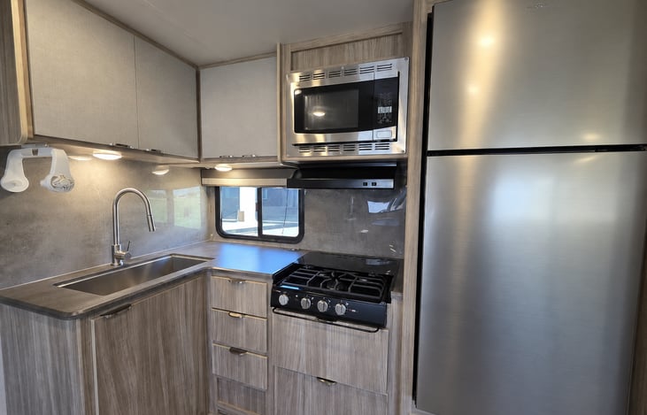 Kitchen Galley-featuring the large sink, convection microwave, spacious fridge, and stovetop. Drawers and cabinets are stocked with everything you need to make cooking a breeze