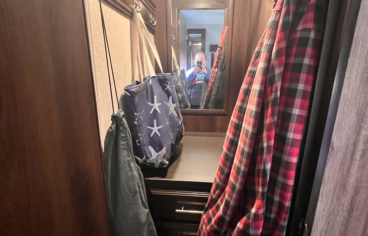 Full closet in the private bedroom with a dresser, mirror and a hanging bar.