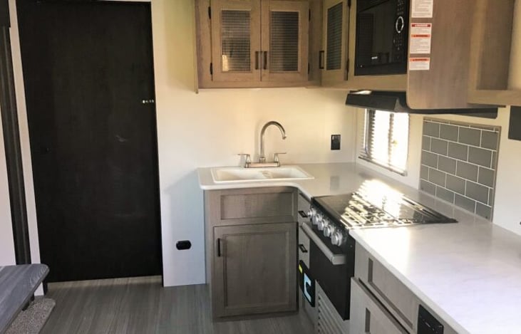 Kitchen Area with cabinets over counter, 4 burner stove microwave and oven.