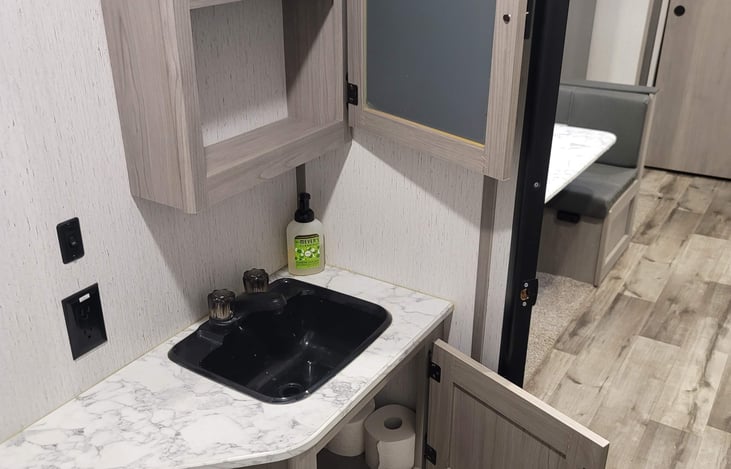 Bathroom sink and storage above and below.