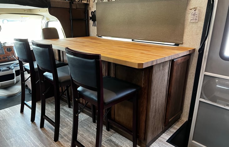 Seating for three at the bar with a TV that raises and lowers.  TV has been lowered into the bar to allow more counter space.