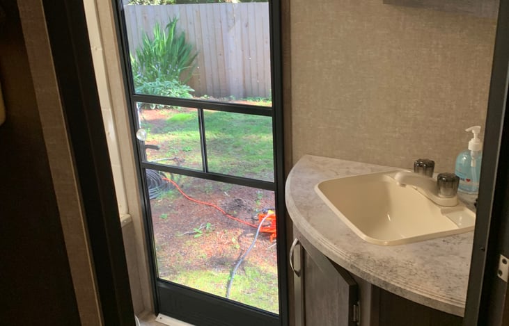 Door exiting the bathroom from rear of trailer. 
Bathroom sink with storage.