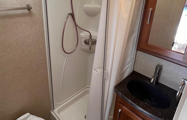 Bathroom with shower, toilet, sink and vanity, &fully stocked w towels