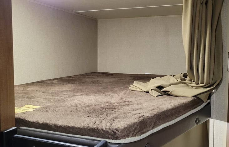 The top bed of the bunk bed in the camper. This is located in the back left side when walking into the camper