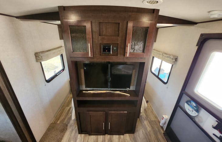 A full view of the entertainment center, door, and entryway into the private bedroom (doors not shown)