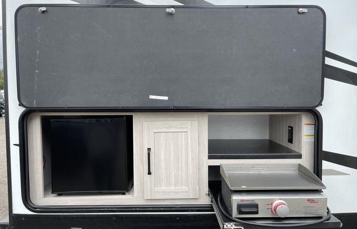 Outdoor kitchen with refrigerator. Griddle connects via LP quick-connect under the camper and is fueled by the LP tanks on the front of the trailer.