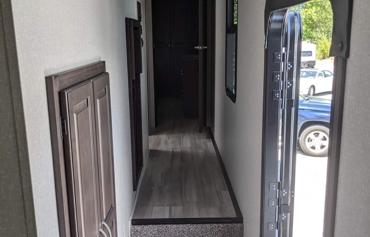 Main entrance and small storage cabinet. Steps leading to bathroom and master bedroom