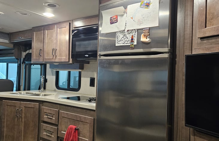 Kitchen with full size refrigerator and freezer, sink, cooktop, and microwave.