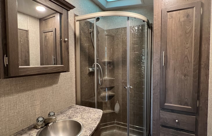 Spacious bathroom accessible from hallway or master suite offers ample counter space, undercounter storage, medicine cabinet, reach-in closet with hangers, shower with removable shower head and toilet