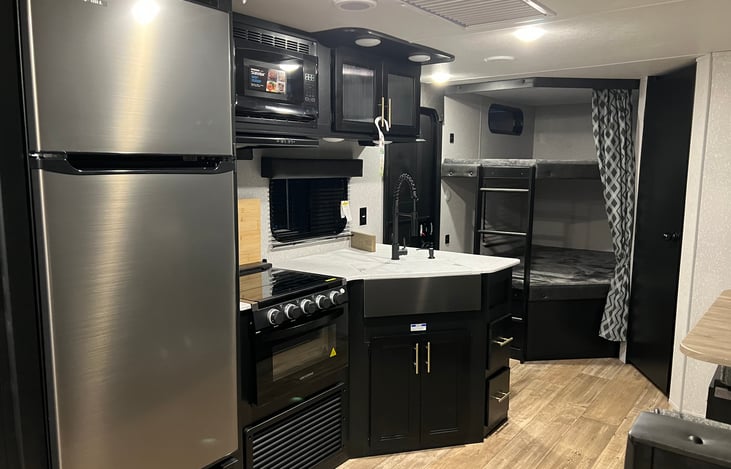 Gas stove and oven. Microwave and fridge at the ready. Fully stocked kitchen. 
Bunks in background. Bottom can accommodate two adults and top two smaller persons.