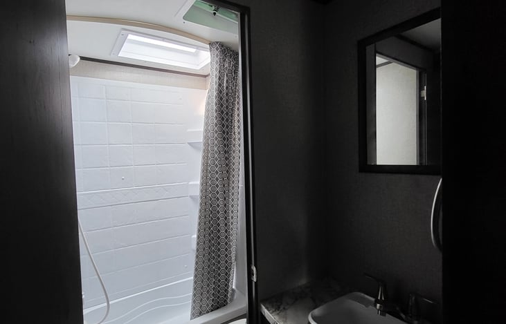 Bathroom with toilet, tub and shower. Also has skylights and fan