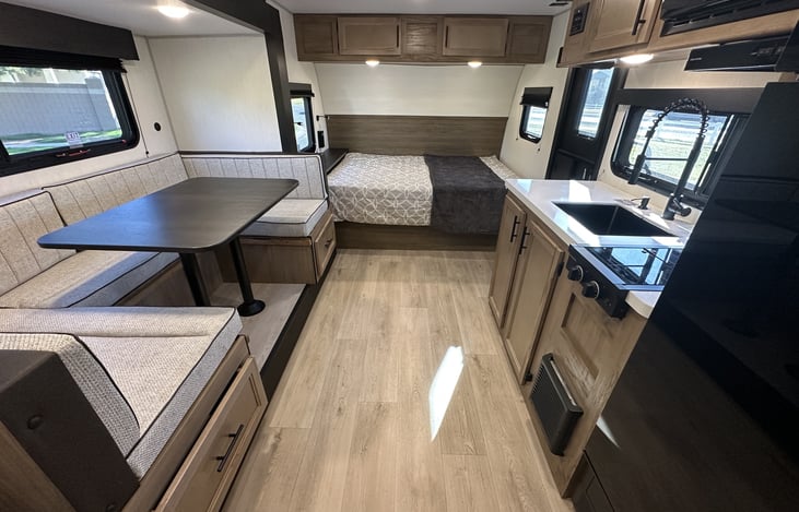 Interior overview showing dinette, kitchen, queen bed, and bright windows.