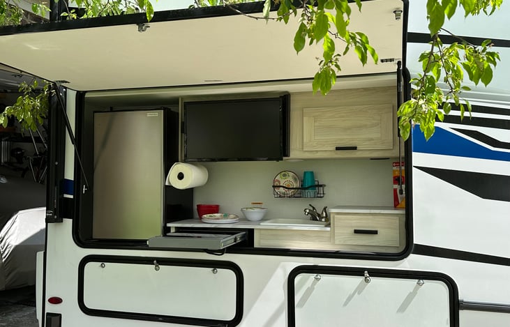 Outdoor kitchen has beverage refrig., pullout induction burner, outdoor kitchen needs, storage, and tv with remote