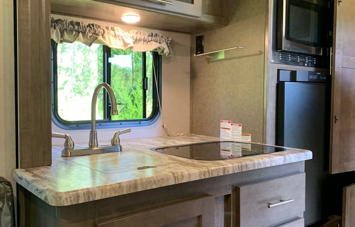 2 burner gas cooktop, sink, and storage, fridge has a small convertible freezer compartment, convection microwave oven