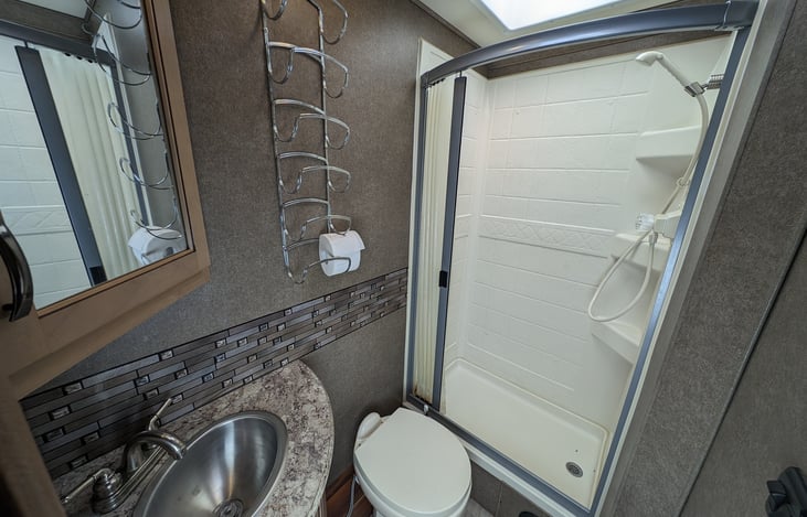 Clean bathroom with nice tile accents and large shower with handheld shower head
