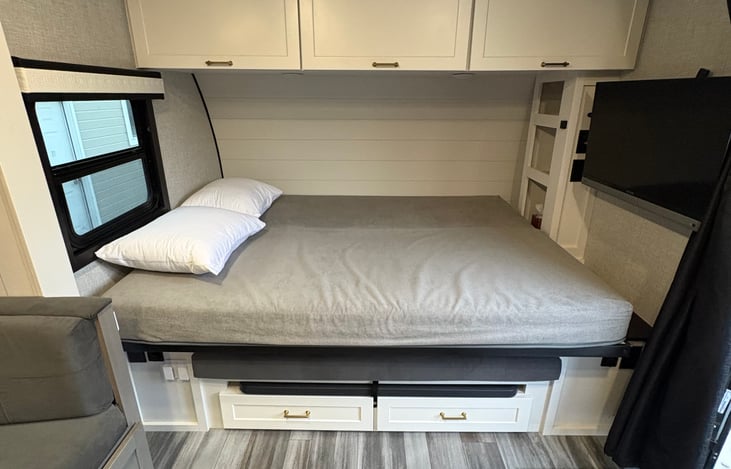 Foldable queen bed with pillows and linens.