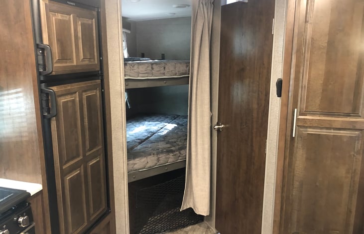 twin double bunks. Fridge is to the left. Bathroom door is on the right.