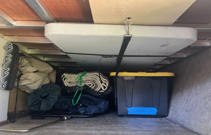 Front cubby, with fishing pole rack, 4' table, chairs & patio rug.