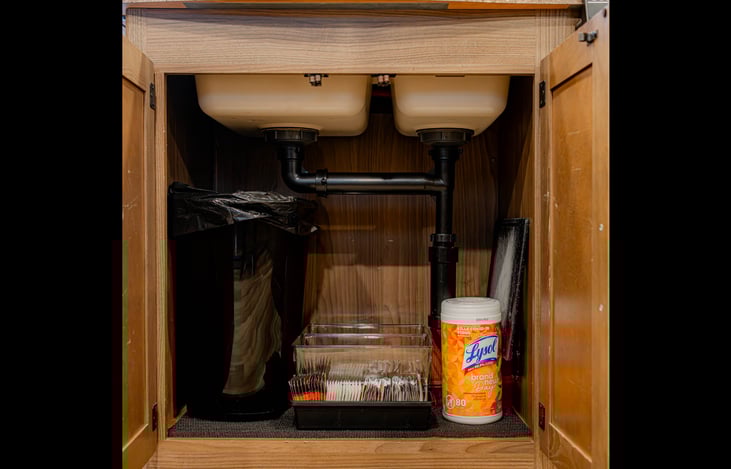 Under sink storage includes a small trash bin, coffee supplies, and cleaning essentials organized and easy to access during your travels
