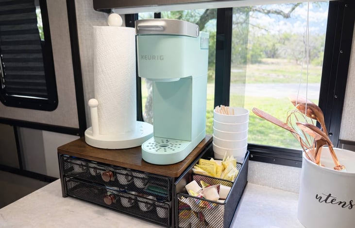 Single-serve coffee maker with a variety of coffee pods, creamer, sugar, cups, and hot chocolate provided.