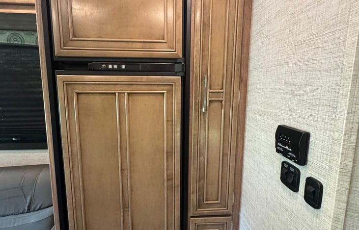 Fridge and side pantry with the view of the thermostat and light switch.