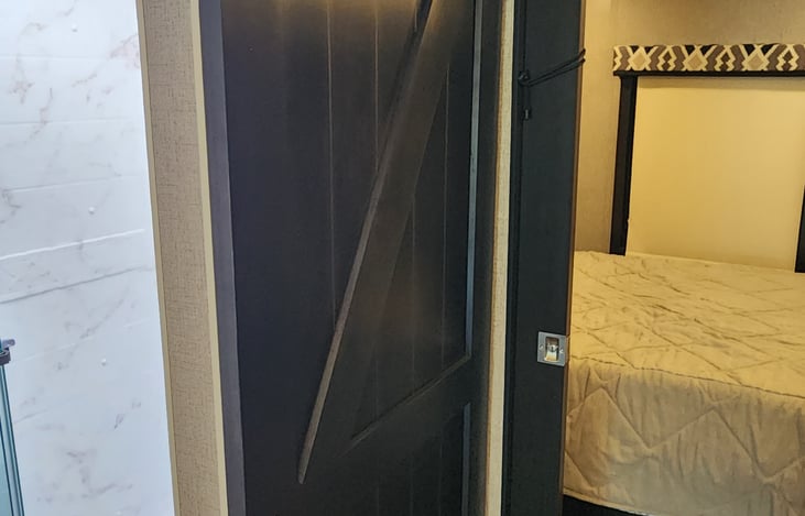 Bedroom and bathroom have the modern farmhouse style privacy doors.