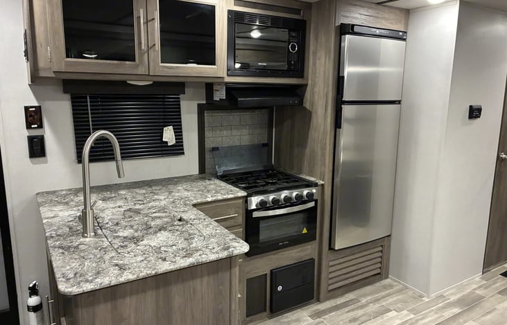 The fully equipped kitchen makes cooking on the road simple and enjoyable. It includes a stovetop, oven, microwave, and refrigerator, plus ample counter space for preparing meals.
